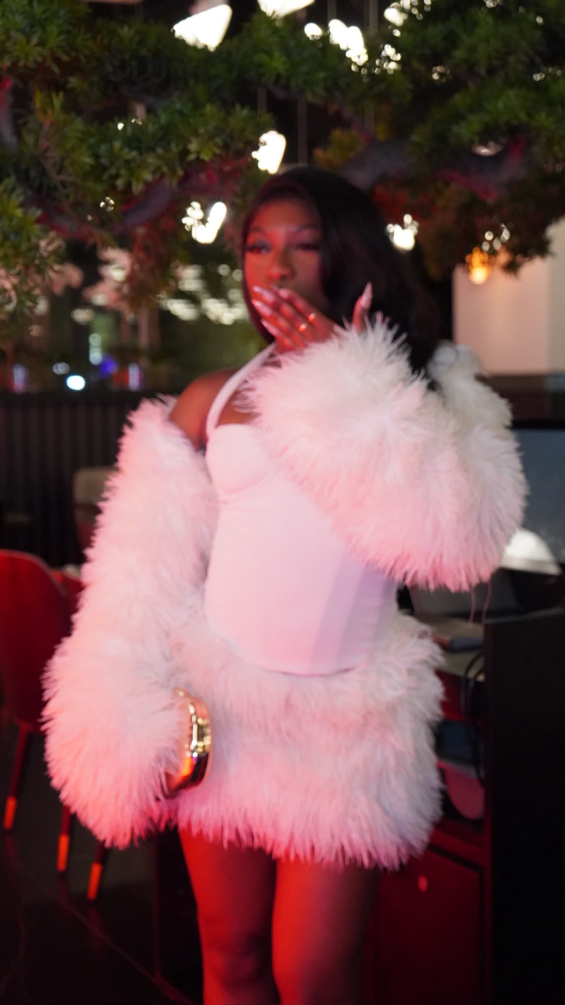 Mya, wearing a pink faux fur coat